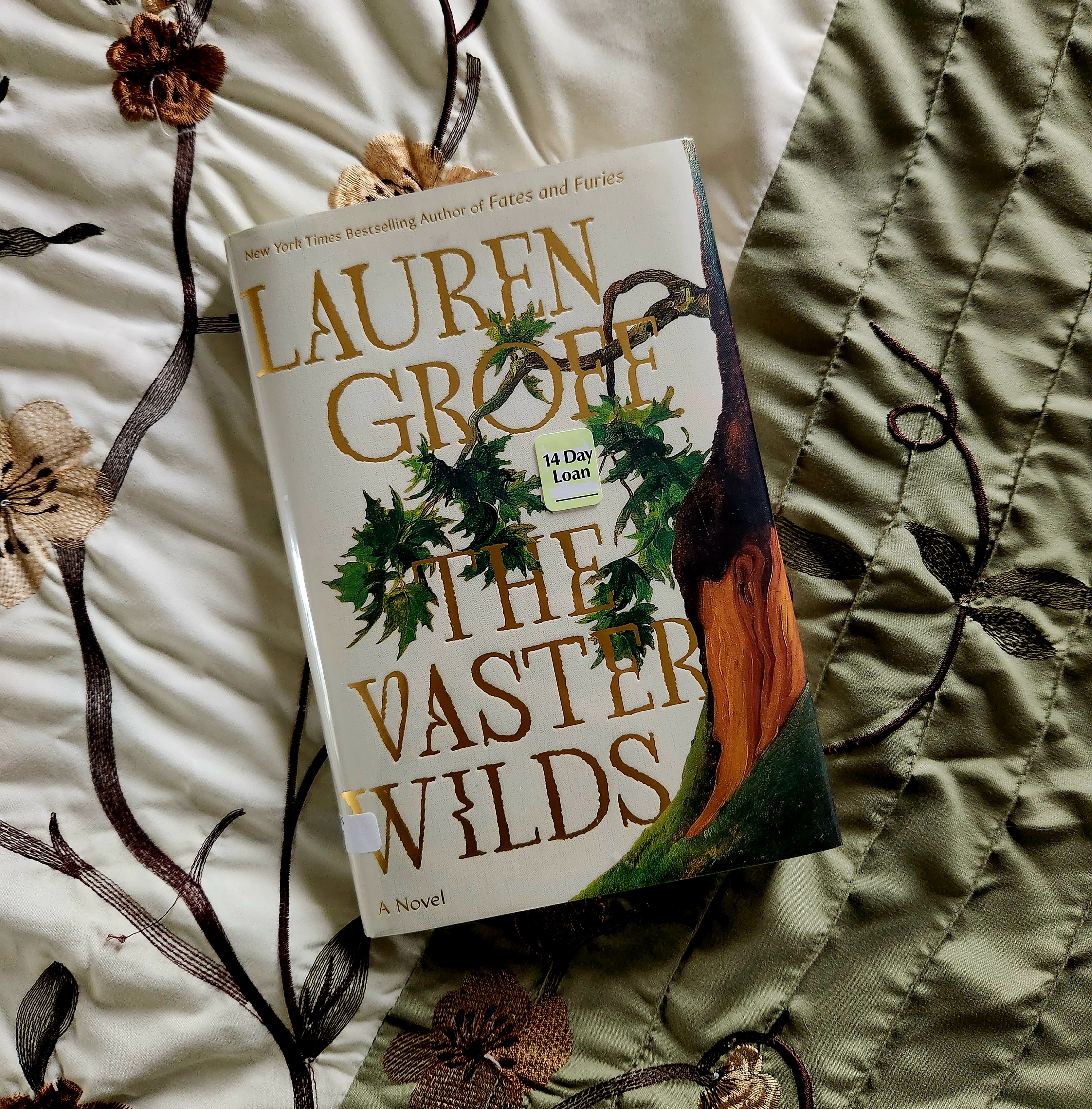 Book cover of The Vaster Wilds on a green and white bedspread