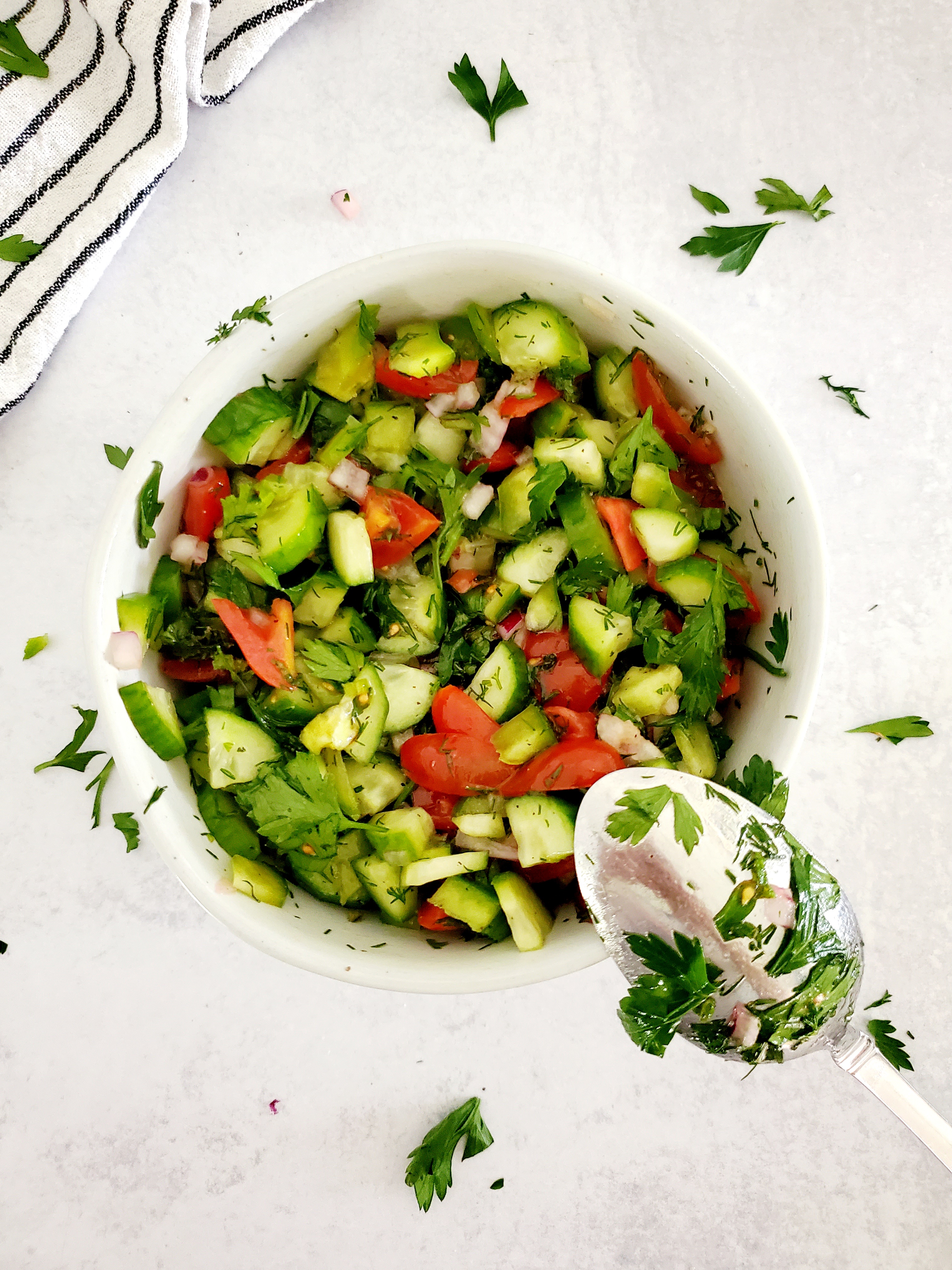 Classic Shepherd's Salad in a bowl with a spoon on Replica Surfaces background