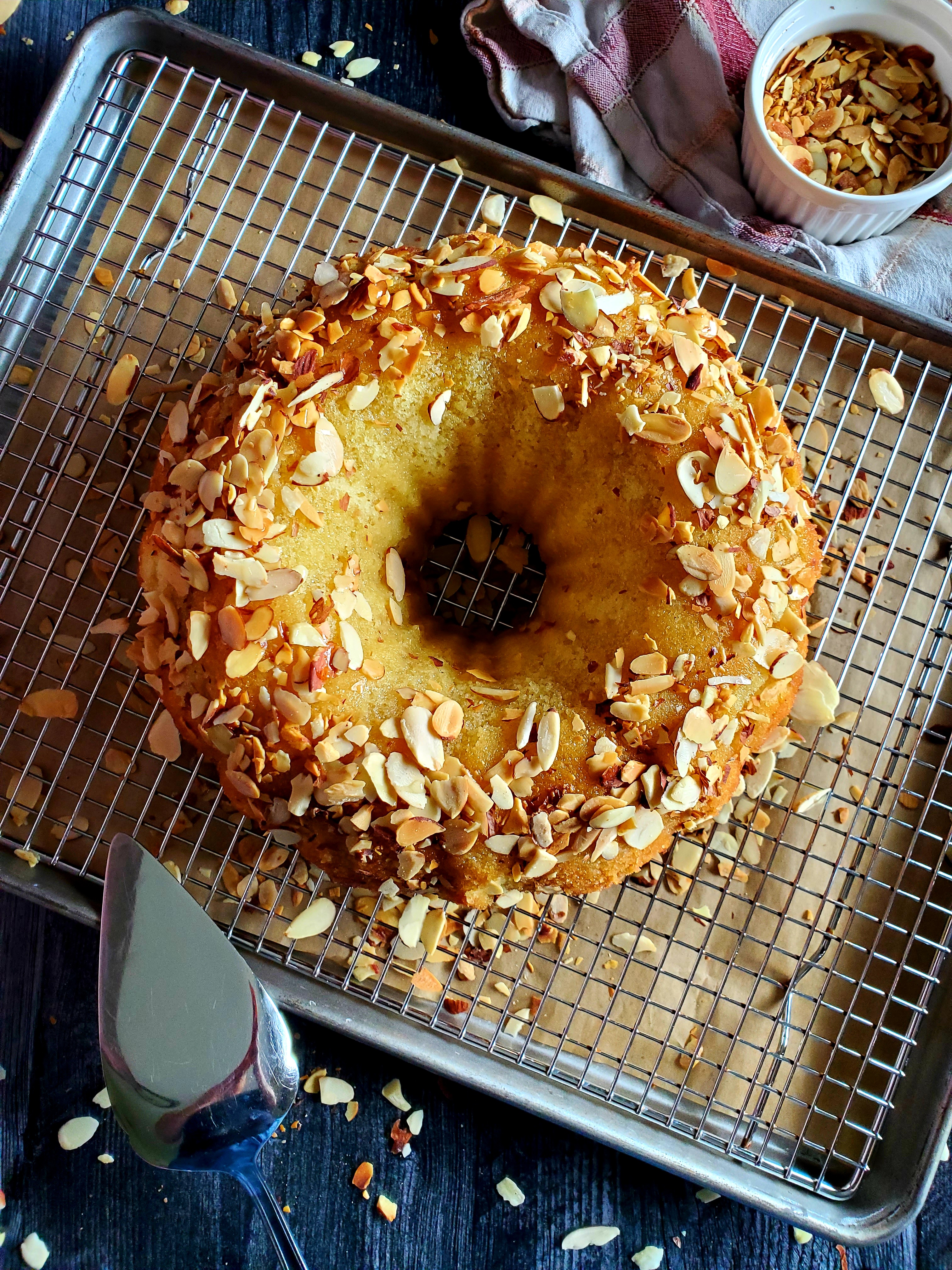 Almond Kentucky butter cake with cake cutter on cooling rack and sheet pan