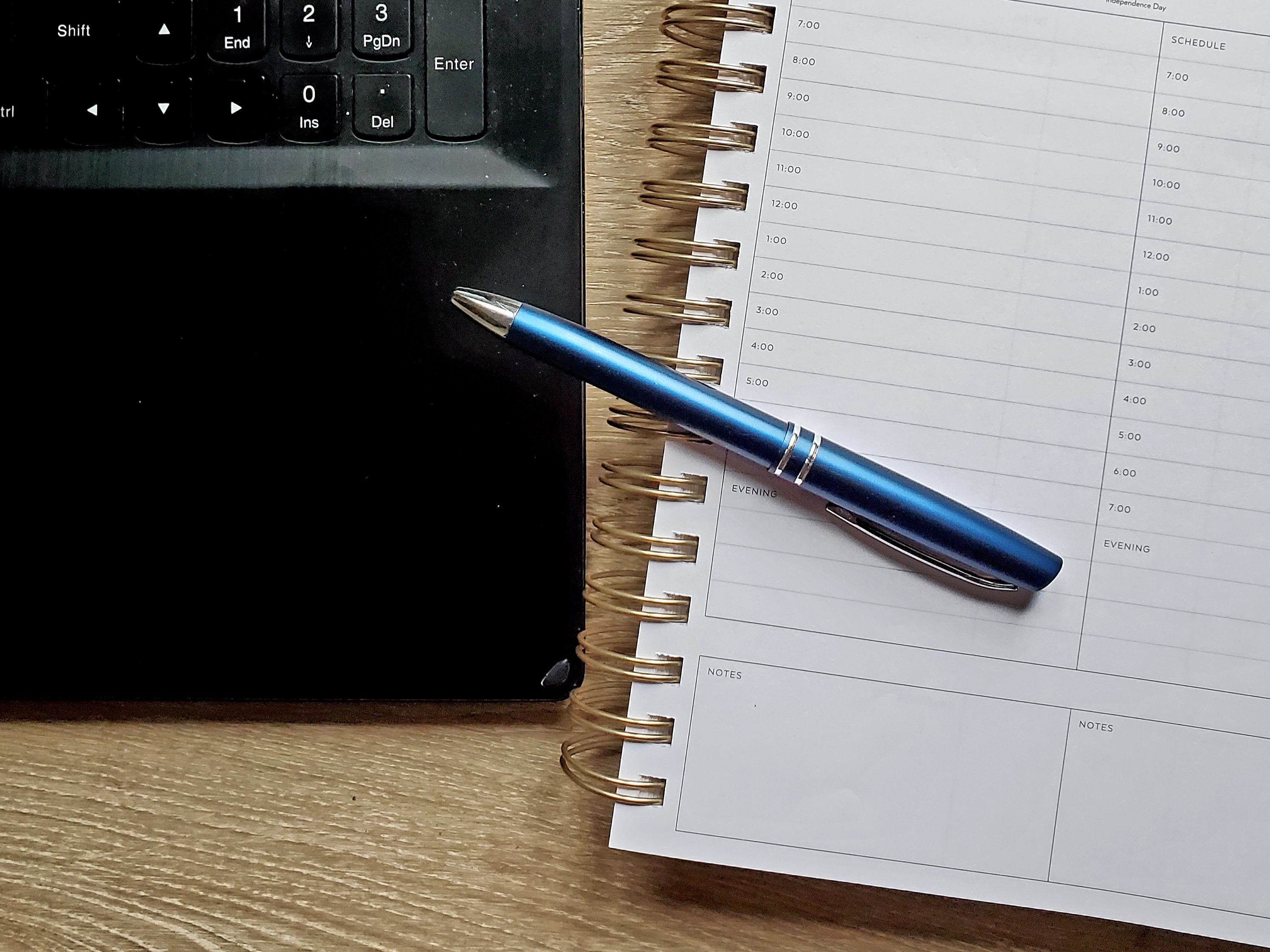 laptop edge and notebook with blue pen